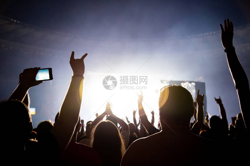 音乐会人群的剪影观众为舞台上的音乐家鼓掌明亮的聚光灯照在跳图片