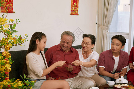 在月新年庆祝活动上向祖父母提供传统资金信封的老年夫妇背景图片