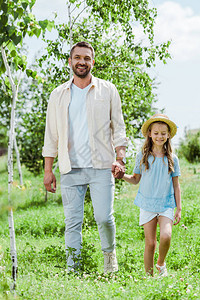 幸福的父亲和女儿站在绿色植物附图片