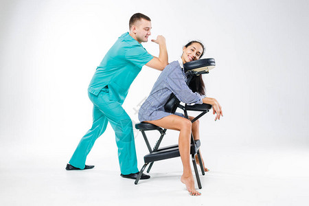 身穿蓝色西装的男治疗师为年轻女工做背部和颈部按摩图片