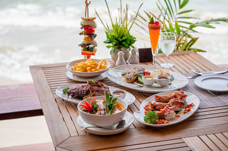 热带海餐桌上食物烤猪排牛肉排海鲜和辣图片