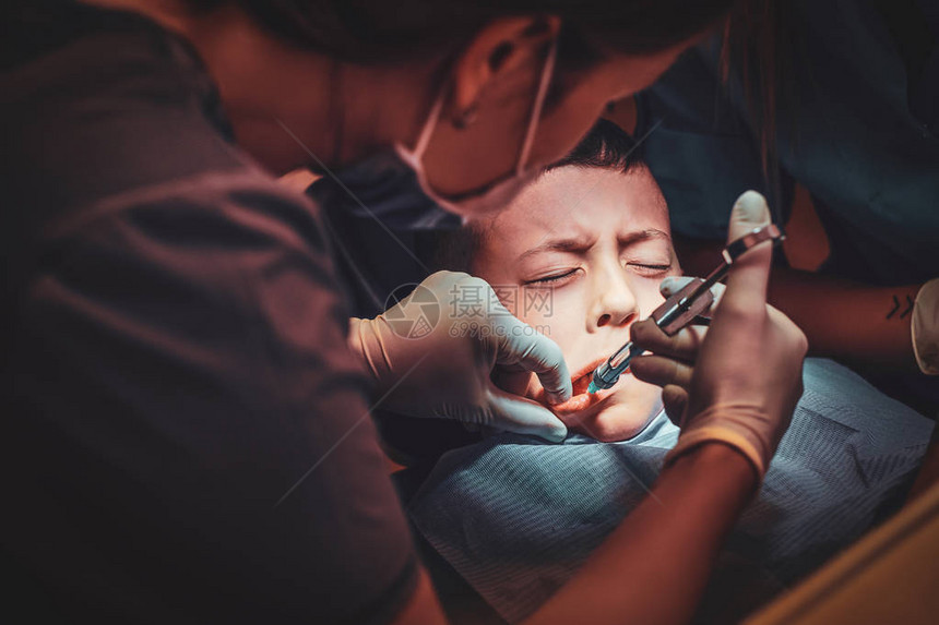 害怕的小孩子通过有经验的牙医注射针图片