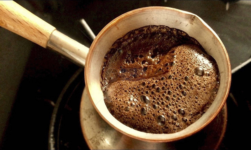 咖啡师用铜土耳其人准备热可口的饮料图片