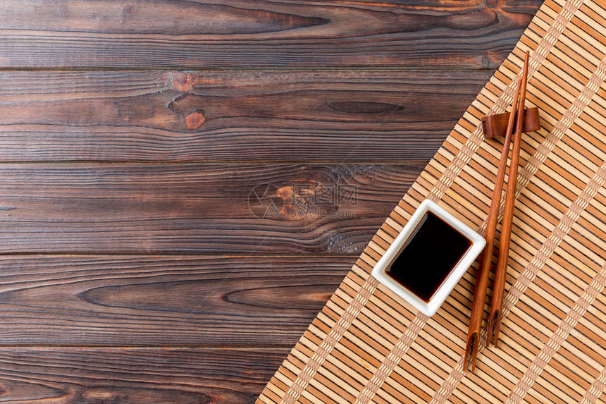 竹席和酱油与寿司筷子木制的桌子上带有寿司复制空间背景的图片