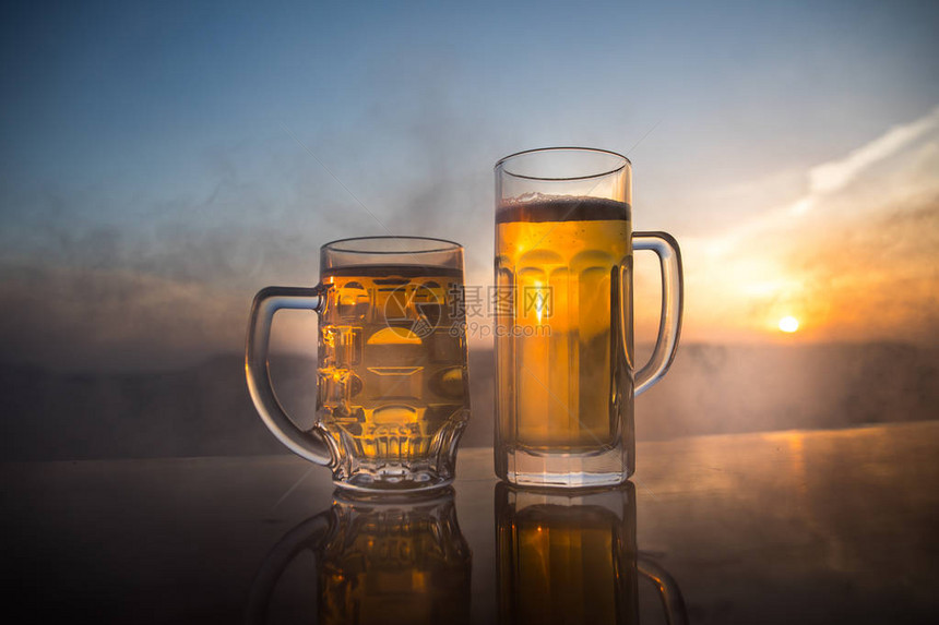 日落时在海滩上喝啤酒冷却夏季饮料概念关闭一杯DraugtBeer和阳光背景的Bokeh图片