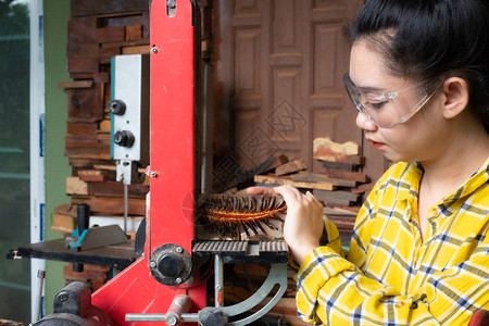 站立的木匠妇女正在用砂纸油机能工具在工作长椅上手工艺图片
