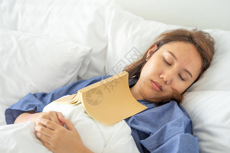 亚洲女孩睡觉时看书人书封面嗜睡导致睡眠充足睡眠的概背景图片