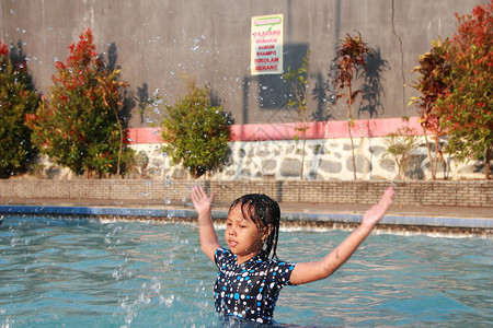 一个小女孩在游泳池里玩水感觉快乐图片