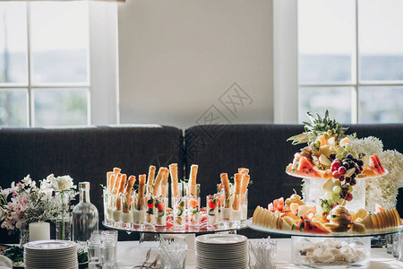 西红柿罗勒奶酪熏火腿绿色植物面包和水果开胃菜在婚礼或圣诞盛宴的餐桌上图片