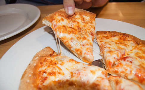 奶酪伸手去拿一块新鲜出炉的热比萨饼图片