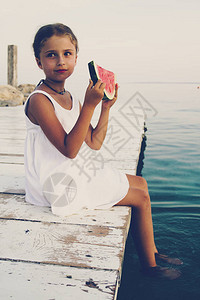 女孩拿着西瓜坐在木桥上暑假沙滩清新浅图片