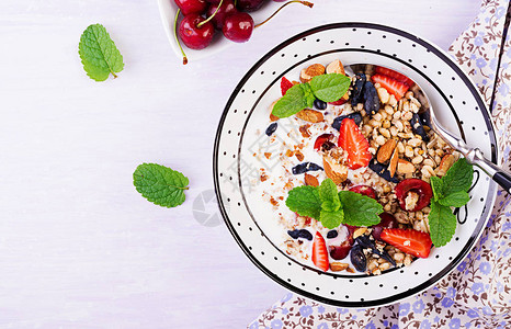 健康早餐格兰诺拉麦片草莓樱桃金银花浆果坚果和酸奶在碗里素食概念图片