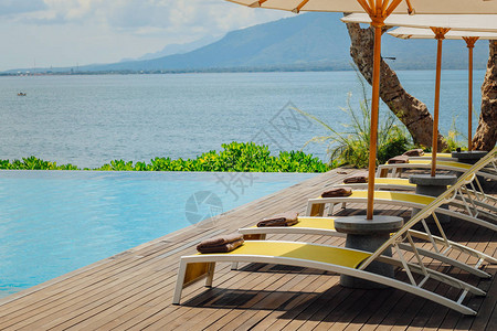 酒店或度假村的美丽热带游泳池配有雨伞椰子树躺椅棕榈树图片