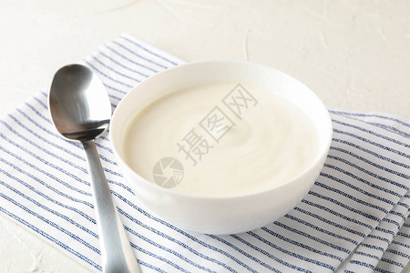 一碗酸奶油酸奶勺子和毛巾放在白图片