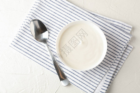 一碗酸奶油酸奶勺子和毛巾放在白图片