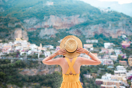 身着草帽和黄色洋装的年轻女背影与背景上波西塔诺村的波西塔诺村图片