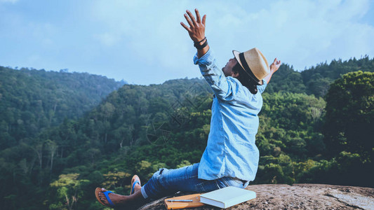 亚洲人旅行在假期放松座位放松在岩石峭壁上看书在山上的夏天教育图片