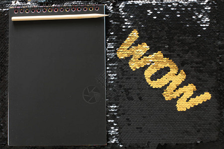 黑色亮片背景的金色亮片WOW字母黑布笔记板和填入的图片