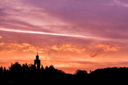 教堂和森林地平线的黑色轮廓在金色的夕阳天空上图片