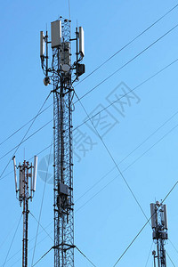 在一座针对蓝色天空的多层城市住宅建筑屋顶上安装移动电话天线设备图片