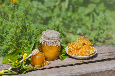 在质朴的木桌背景上用蜂蜜北斗的罐子里的蜂蜜梳子里的甜蜂蜜健康食品的概念由有机成分制背景图片