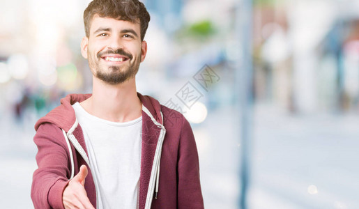身处孤立背景的英俊男青年微笑友好地互握手作为问候和欢迎成功的生意图片