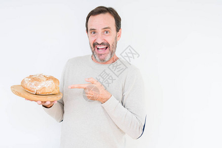 在孤立的背景中举着自制新鲜面包的老年人非常快乐地用手图片