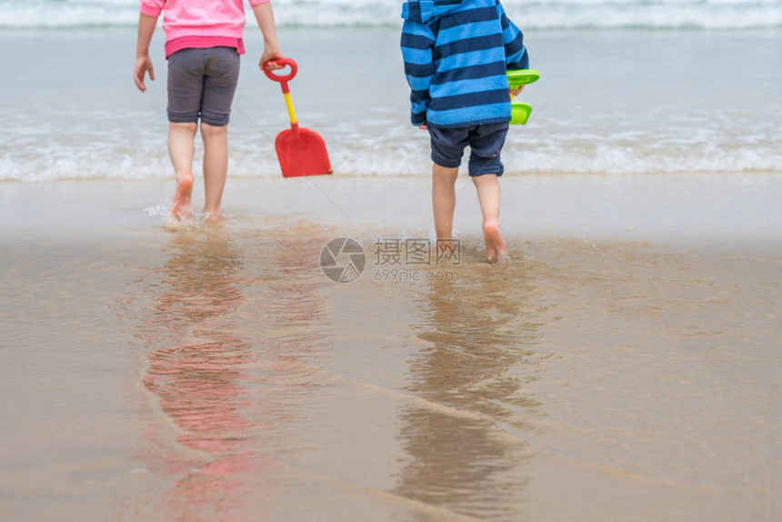 夏天在沙滩上水中玩弄多彩的塑料玩具铲子的图片