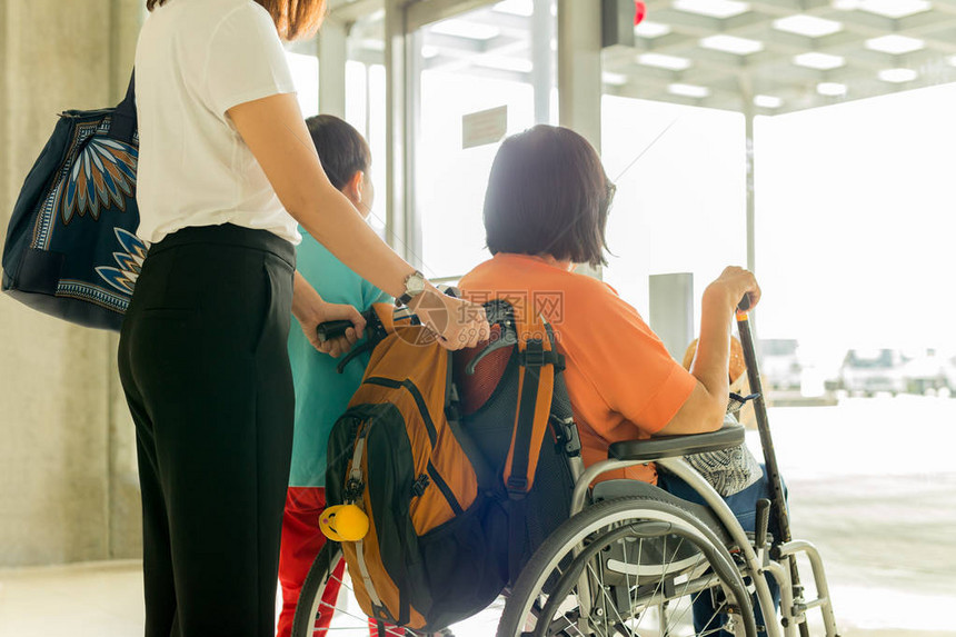 在国际机场等待登机的轮椅上与儿子和母亲一起图片