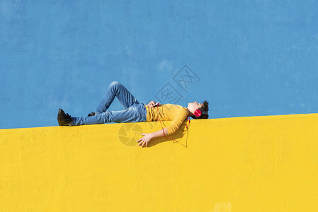 一个穿着休闲服的小男孩躺在黄色栅栏上图片