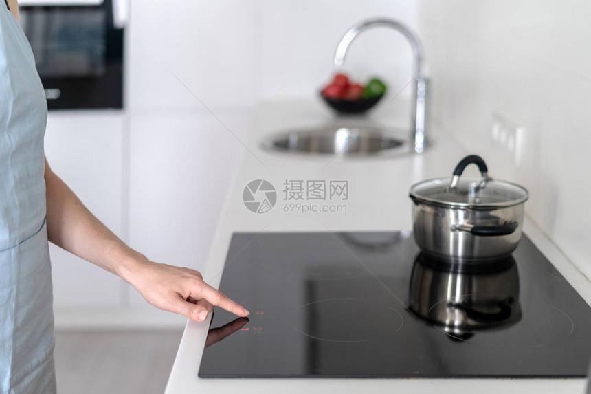 妇女用在炉子上加酱锅的炉子选择烹饪节目站立在现代白色的切图片