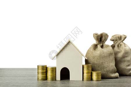 存钱住房贷款抵押贷款未来概念的房地产投资一个住宅模型与堆栈的硬币和钱袋子在木桌上孤立在白色一项背景图片
