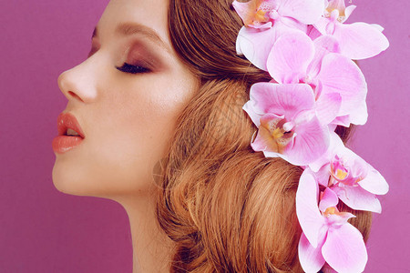 粉红色背景上的黑发女郎专业化妆和发型的女孩发型设计图片