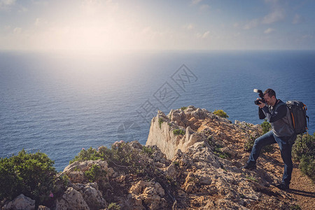 站在悬崖边缘的观光客拍摄了希腊特岛夏季在海难湾令背景图片