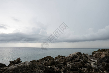 前景是岩石海岸远处是海洋和云层图片