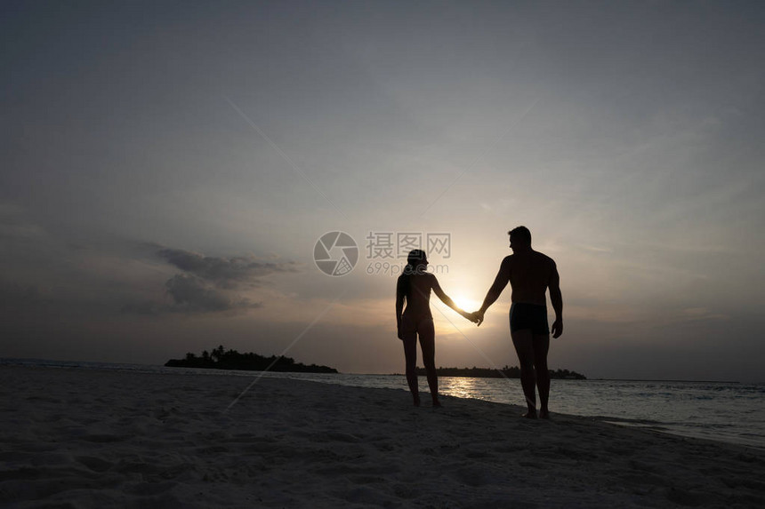 日落时一对情侣握手的情侣在阳光下一个男人和一图片