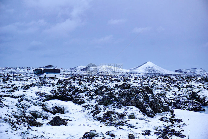 两辆Busses站在蓝色环礁地区美丽的冰岛地貌中部带雪覆图片