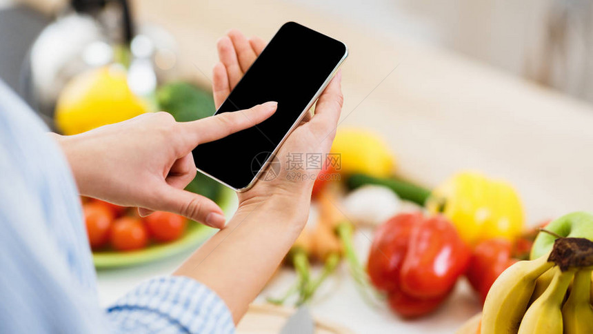 搜索食谱妇女使用智能手机烹饪食物图片