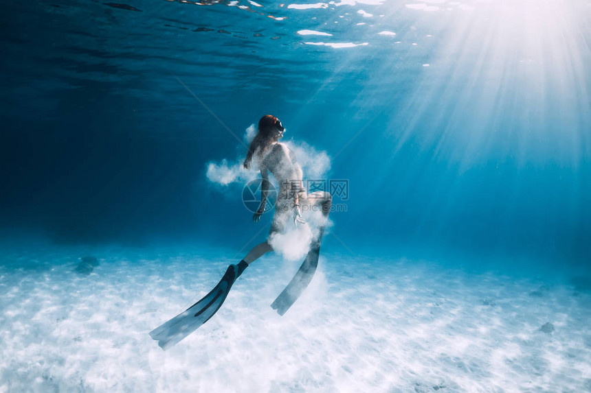 女自由潜水者在沙海上方有鳍和白沙子图片