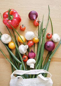 桌子上的生态袋红洋葱红辣椒蘑菇和樱桃番茄的一套产品图片