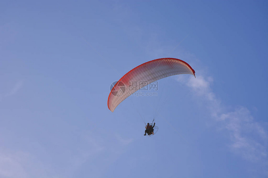 Paramotor有权力的滑翔伞与红色白降落伞在空中飞图片