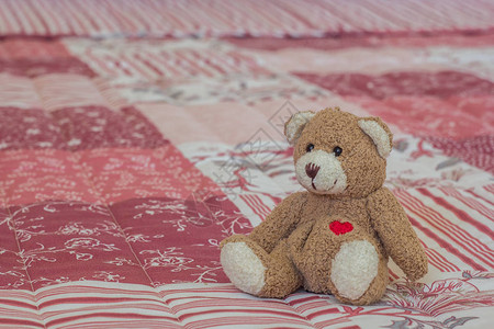 酒店粉红色和白色床单上的玩具熊图片
