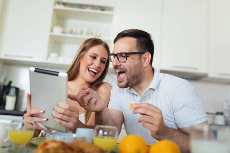快乐的情侣一起在家享受早餐时间并使用图片