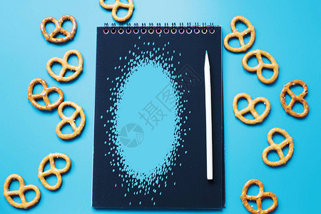亮蓝色背景上带有空白黑纸木刮板和饼干的记事本图片