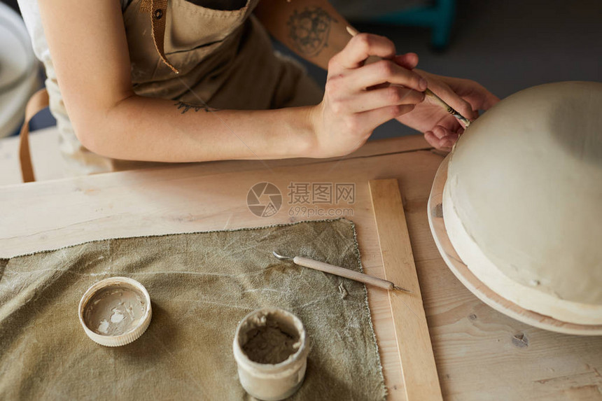 高角关闭了无法辨认的女工匠在陶器轮上手工制作碗图片