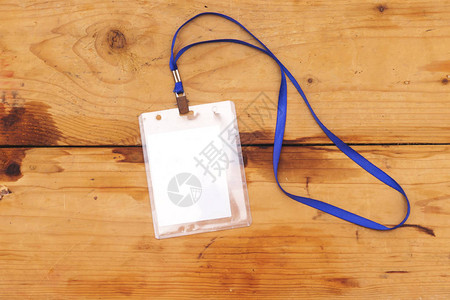 空白徽章样机隔离在木制背景上用绳子挂在脖子上的普通空名牌模拟名称标背景图片