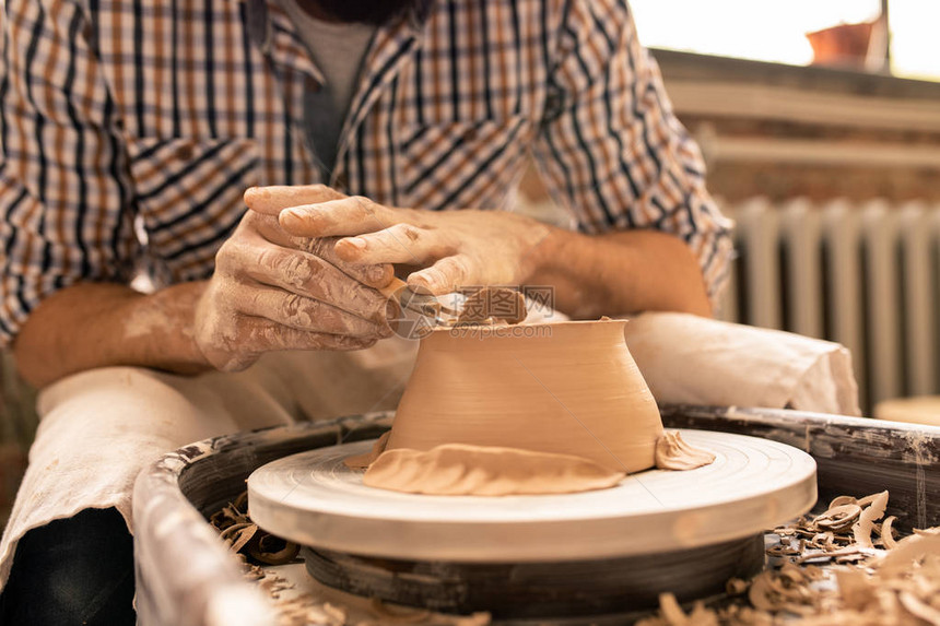 当代年轻陶匠用特别的手凳子压扁新粘土碗底部图片