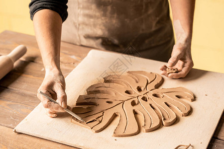 设计期间用铅笔指着木板上叶子形状的粘土制品的创意图片