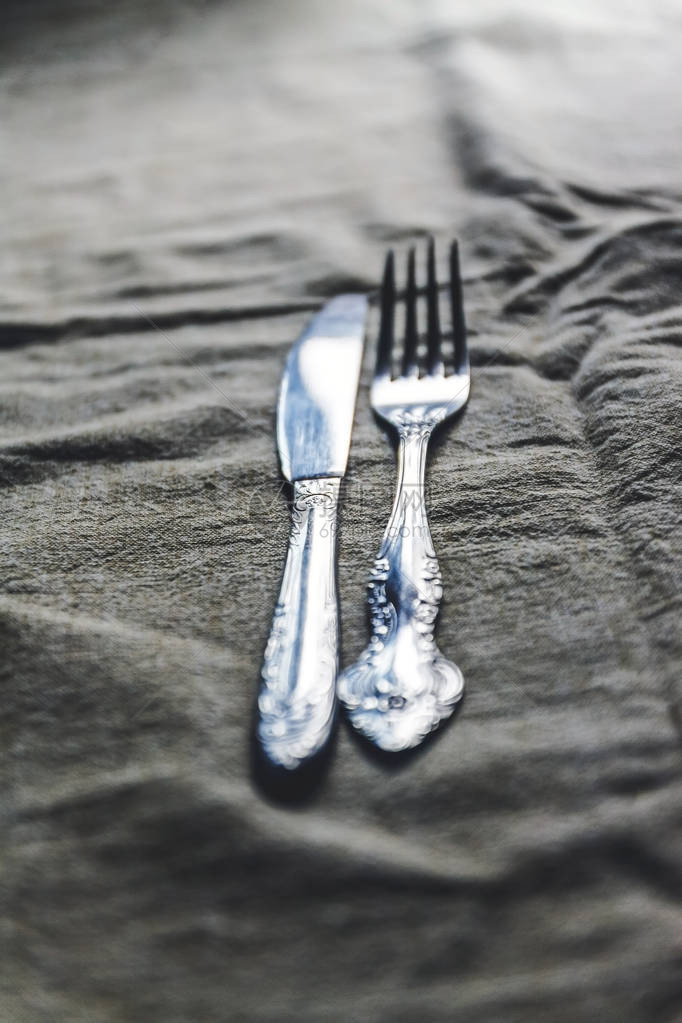 复古老式餐具刀叉在古董桌布上图片