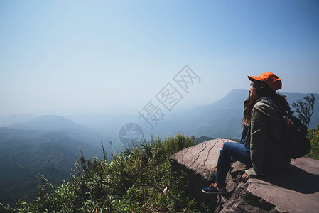 亚洲女旅行在假期放松坐在山上看风景山公园开心在山上图片
